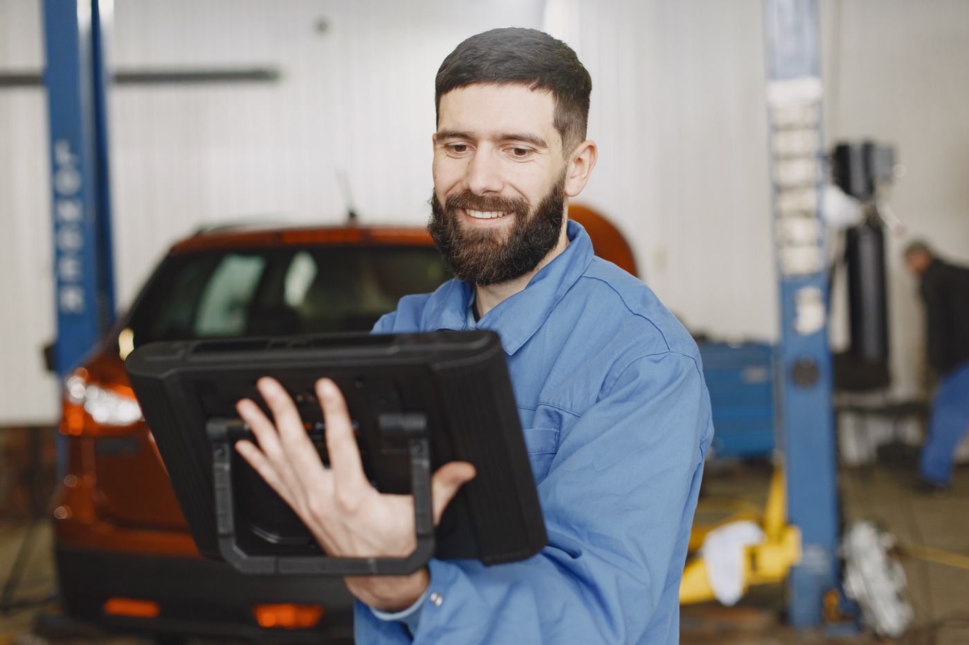 Technicien souriant d'une agence partenaire, valise de diagnostic à la main