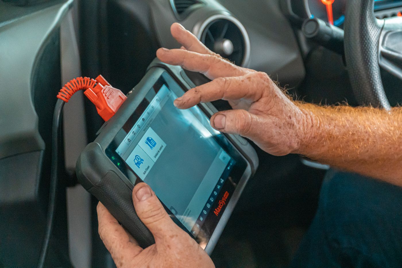 Valise de diagnostic branchée sur la prise OBD, dans l'habitacle d'une voiture